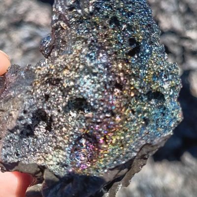 a hand holding a piece of cake on a rock